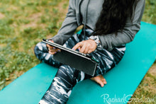 Load image into Gallery viewer, black and women's leggings by Canadian Artist Rachael Grad on women seated yoga mat