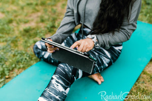 black and women's leggings by Canadian Artist Rachael Grad on women seated yoga mat